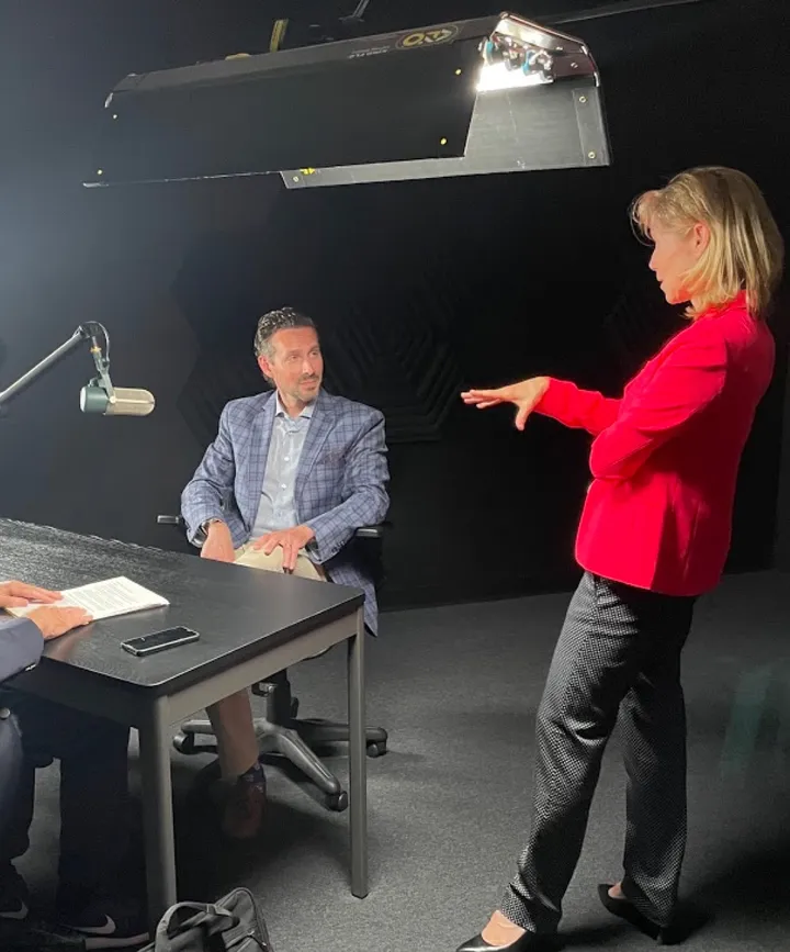 A doctor being interviewed on the Dental Implants Today set while a media trainer gives direction